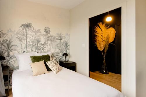 - une chambre avec un lit blanc et un papier peint tropical dans l'établissement La Villa l'Escale, somptueuse maison contemporaine, à Angoulême