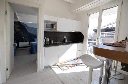 a kitchen with white cabinets and a table and a chair at Room Ravello in SantʼAntonio Abate