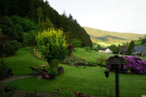 a garden with a green lawn with a tree and flowers at Kandel - Stubenhof, Black Forest in Simonswald