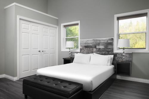 a white bedroom with a white bed and a black stool at Samuels Boutique Hotel in Goderich