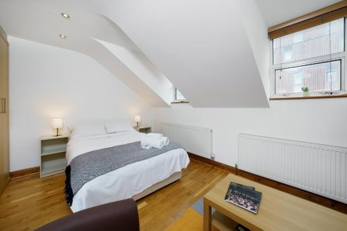 a white bedroom with a bed and two windows at Flat in London in London