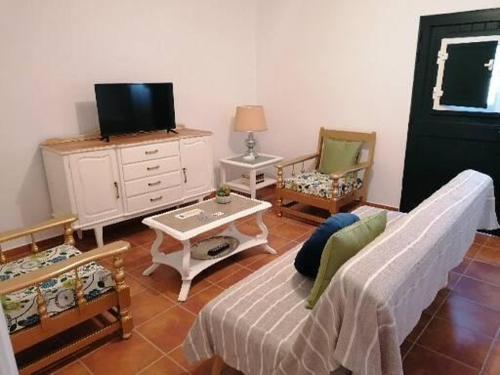 uma sala de estar com um sofá e uma televisão em A casa da Carolina II em Mértola