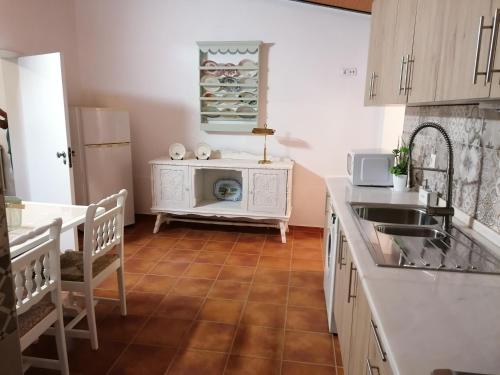 cocina con armarios blancos y suelo de baldosa en A casa da Carolina II, en Mértola