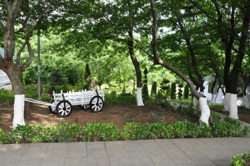 a white bench sitting in a park with trees at Vilesh Palace Hotel in Masallı