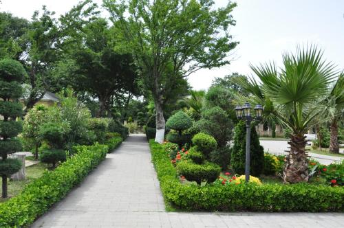 a walkway through a garden with trees and bushes at Vilesh Palace Hotel in Masallı