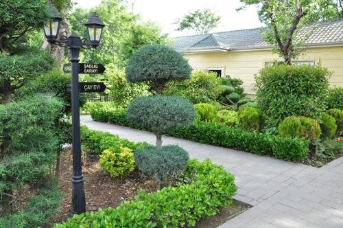 a street light with street signs in a garden at Vilesh Palace Hotel in Masallı