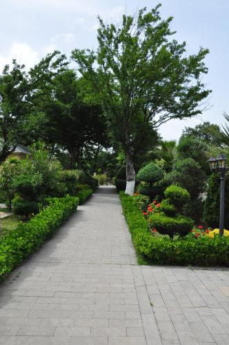 a walking path in a park with trees and flowers at Vilesh Palace Hotel in Masallı