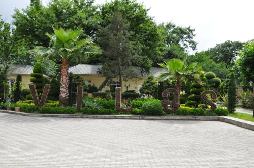 a garden with palm trees and a house at Vilesh Palace Hotel in Masallı