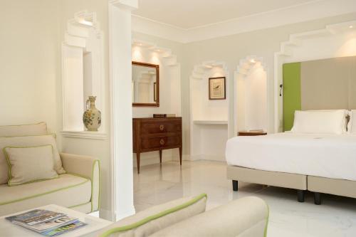 a bedroom with a bed and a couch and a chair at Grand Hotel Royal in Sorrento