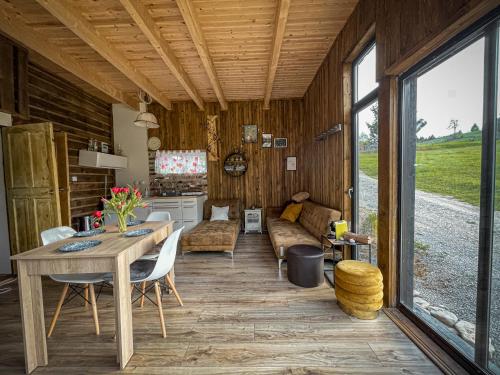 a dining room and living room of a log cabin at Panoramic Noah's Loft in Stînceni