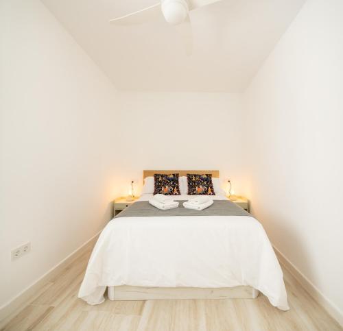 a white bedroom with a bed and two lamps at Suite Catedral Little Apartments in Cádiz