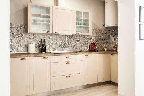 a kitchen with white cabinets and floral wallpaper at Suite Catedral Little Apartments in Cádiz
