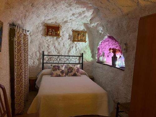 um quarto com uma cama numa parede de pedra em Casa Cueva La Fuente em Fontanar