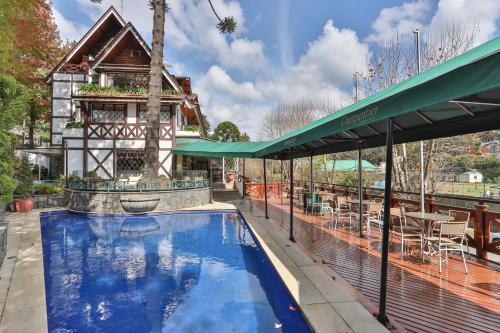 a swimming pool in front of a house at Le Suisse Elegance Hotel in Campos do Jordão