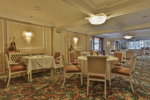 a dining room with tables and chairs and a chandelier at Le Suisse Elegance Hotel in Campos do Jordão