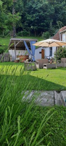 a yard with chairs and an umbrella and a house at Kiskilenc Vendégház in Szarvaskő