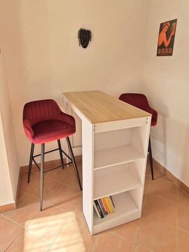 a desk with two chairs and a book shelf at Apartman Szeged szívében in Szeged