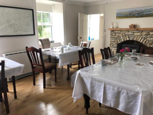 uma sala de jantar com duas mesas e uma lareira em Gortamullen House, Kenmare em Kenmare