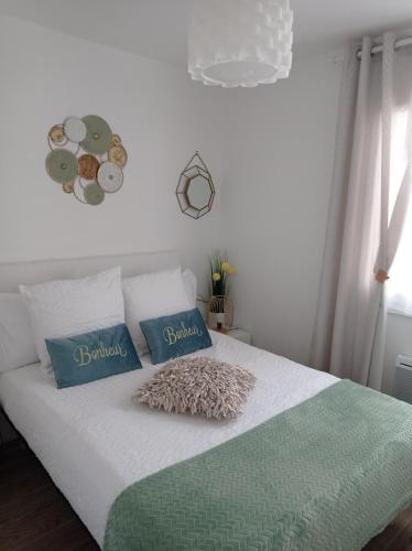 - un lit blanc avec 2 oreillers bleus dans l'établissement Appartement JADE dans résidence proche Tennis/ centre naturiste, au Cap d'Agde