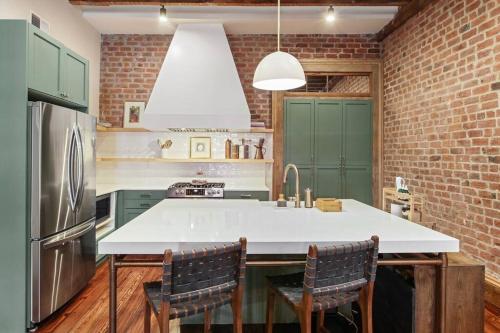 a kitchen with a white counter and a brick wall at Historic Garden District 5BR with Parking and Balcony in New Orleans
