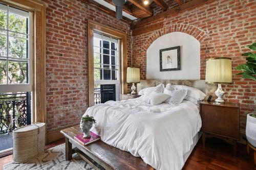 um quarto com uma grande cama branca numa parede de tijolos em Historic Garden District 5BR with Parking and Balcony em Nova Orleans