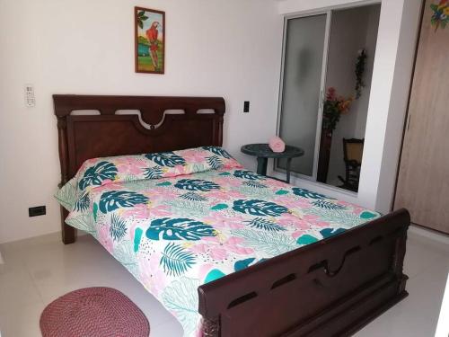 1 Schlafzimmer mit einem Bett mit Blumenbettdecke und einem Spiegel in der Unterkunft Super apartamento en la mejor ubicacion de Cartago in Cartago