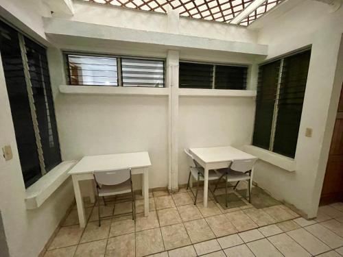 two tables and chairs in a room with windows at Hostal Inn 1 in Flores