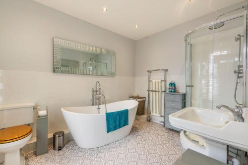 a bathroom with a tub and a toilet and a sink at Cabbell Towers - Norfolk Holiday Properties in Cromer