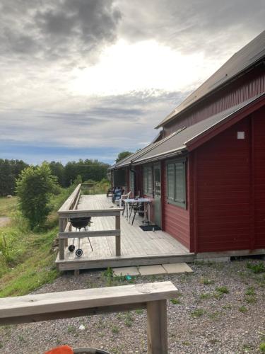 una terraza de madera con mesa y sillas en una casa en Asplunda Gård, Kolmården, stuga nr 3, en Kolmården