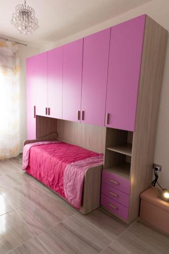 a bedroom with a pink bed and cabinets at L'APPARTAMENTO DEL MARE in Marsala