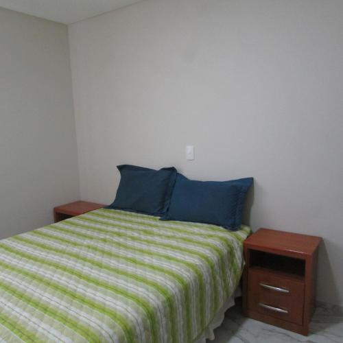 um quarto com uma cama com almofadas azuis e uma mesa de cabeceira em Apartamento em Balneario Camboriu em Balneário Camboriú