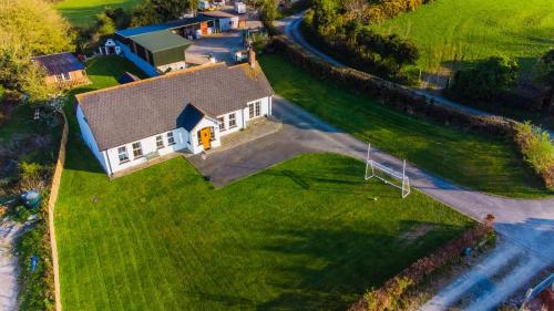 uma vista aérea de uma grande casa branca num campo verde em The Heights & Hollows Farmhouse, Saul, Downpatrick, SLEEPS 14 em Downpatrick
