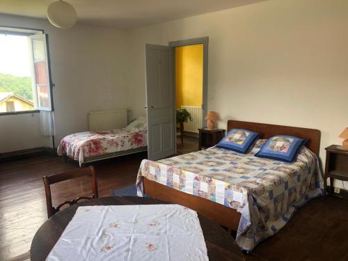 a bedroom with two beds and a table and a window at Un écrin dans la nature in Espelette