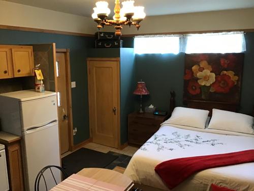 1 dormitorio con 1 cama y cocina con nevera en Chez Odette, loft intime, en Roberval