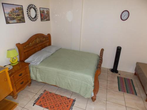 a bedroom with a bed and a table and a clock at Stewart Apt- Trincity, Airport, Washer, Dryer, Office, Cable , WiFi in Trincity 