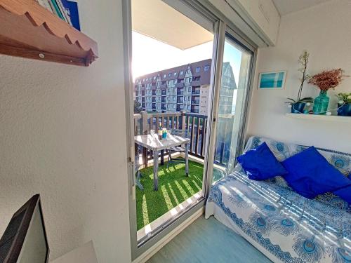 Cette chambre dispose d'un lit et d'un balcon avec une table. dans l'établissement Appartement 3 pièces, vue sur mer piscine tennis proche thalasso, à Cabourg