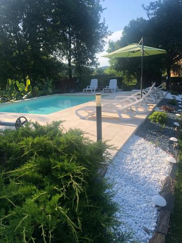 a swimming pool with chairs and an umbrella at Chambres Les Plantous de Severo in Cénac-et-Saint-Julien