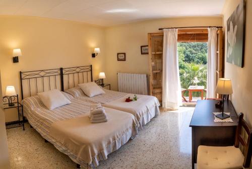 a bedroom with two beds and a desk and a window at Can Rosich in Santa Susanna