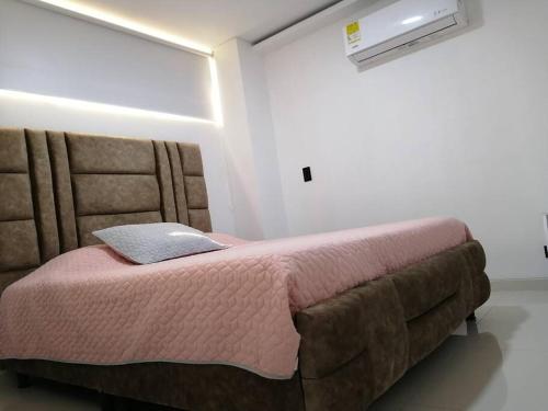 een slaapkamer met een bed met een roze deken bij Apartamento de lujo , con linda vista, cuarto piso in Cartago