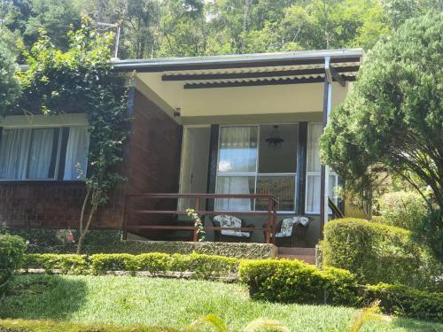 a small house with a porch with a bench at Casa aconchegante com vista para as montanhas in Teresópolis