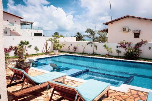 a swimming pool with lounge chairs and a house at Qavi - Leuchtturm House #ParaisoDoBrasil in Parnamirim