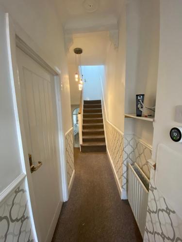 a hallway with stairs leading to a room with a door at The White Room in Plymouth