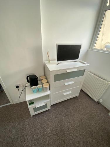 a white cabinet with a tv on top of it at The White Room in Plymouth