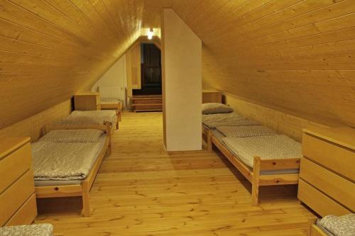 a row of beds in a room with wooden ceilings at Chata Ryba in Pernink