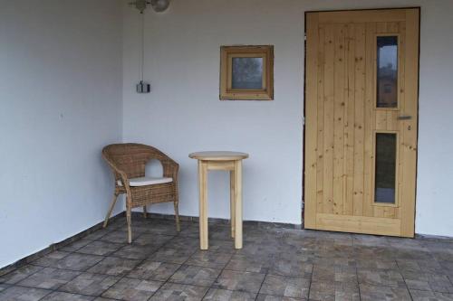 a table and a chair next to a door at Chata Ryba in Pernink