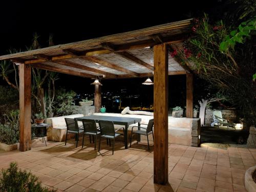 une pergola en bois avec une table et des chaises sur une terrasse dans l'établissement Dammuso Kuddia, à Scauri