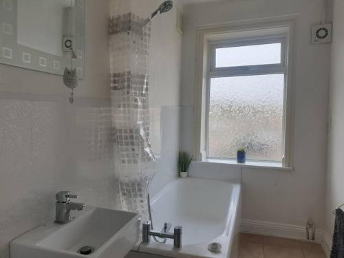 a bathroom with a tub and a sink and a window at Cosy 2 Bedroom City House with 2 Bathrooms in Norwich