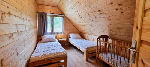 a room with two beds in a wooden cabin at Domki Na Szlaku Bieszczady in Uherce Mineralne (7)