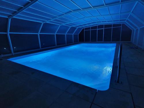 uma piscina num quarto escuro com iluminação azul em Gîte de Chazelpaud em Saint-Bard