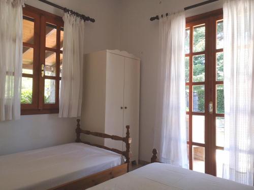 a bedroom with two beds and a cabinet and windows at Villa Lena Entire cottage in Kalamákion